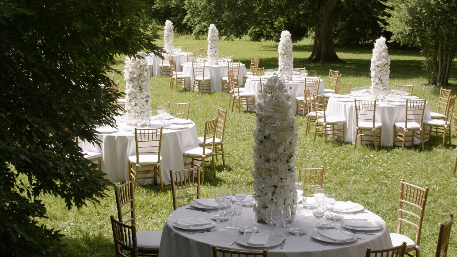 Montaje de boda en el jardín con mesas redondas y centros florales